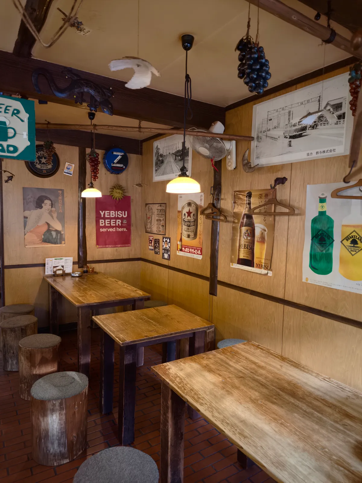 やしまの店内。丸太の椅子と木のテーブル、壁一面のレトロなビールのポスター